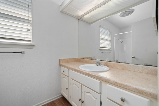 bathroom with walk in shower, vanity, and hardwood / wood-style flooring