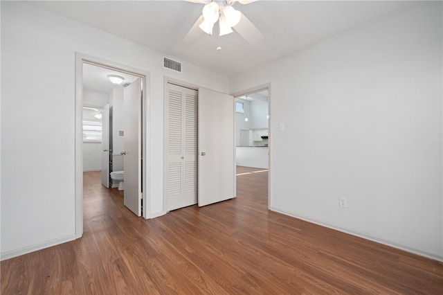 unfurnished bedroom with hardwood / wood-style floors, ensuite bath, ceiling fan, and a closet