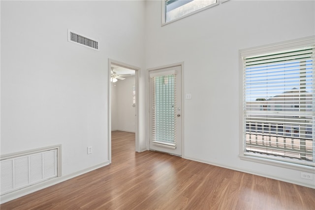 foyer with a towering ceiling, light wood-type flooring, and ceiling fan