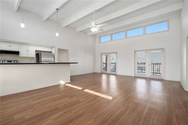 unfurnished living room featuring french doors, a towering ceiling, dark hardwood / wood-style floors, beam ceiling, and ceiling fan