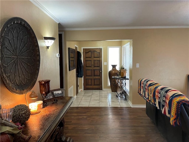 foyer entrance with baseboards, crown molding, visible vents, and light wood-style flooring