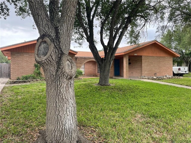 ranch-style home featuring fence, brick siding, and a front yard