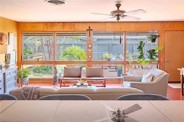 living room with ceiling fan and wooden walls