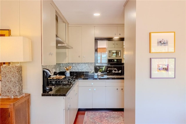 kitchen featuring stainless steel microwave, white cabinetry, black oven, and decorative backsplash