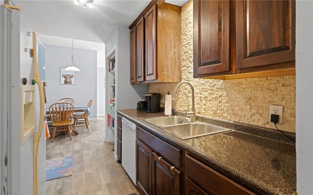 kitchen featuring dark brown cabinetry, sink, backsplash, white appliances, and light wood-type flooring