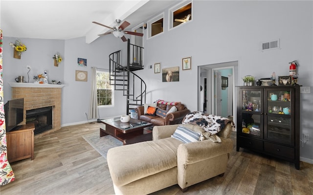 living room with beamed ceiling, ceiling fan, high vaulted ceiling, a fireplace, and wood-type flooring