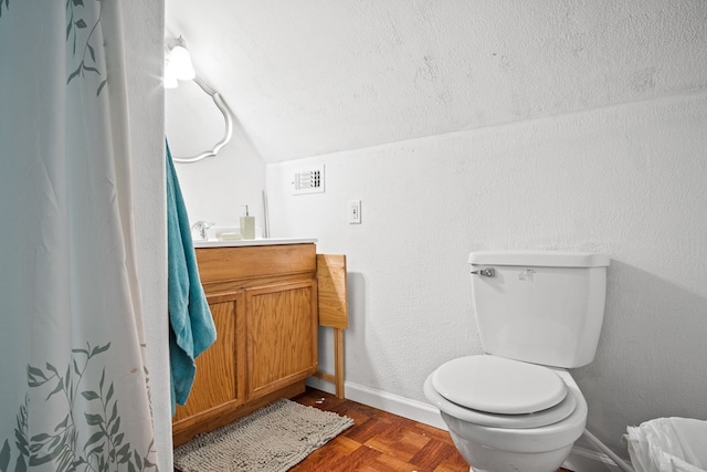 bathroom featuring toilet, vanity, lofted ceiling, and parquet flooring