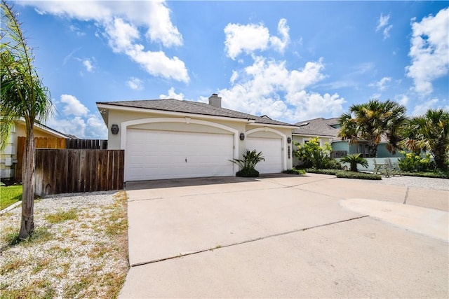 15854 El Soccorro, Corpus Christi, TX 78418 - view of front of house featuring concrete driveway, stucco siding, an attached garage, and a chimney