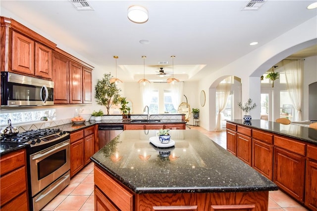 15854 El Soccorro, Corpus Christi, TX 78418 - kitchen featuring appliances with stainless steel finishes, a ceiling fan, a peninsula, a kitchen island, and arched walkways