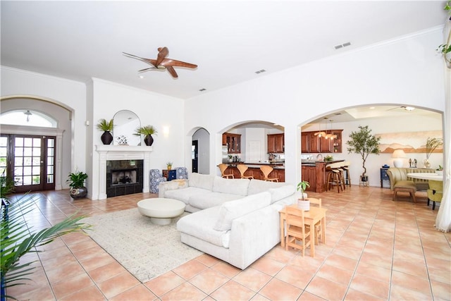 15854 El Soccorro, Corpus Christi, TX 78418 - living area with light tile patterned flooring, a ceiling fan, a tiled fireplace, ornamental molding, and arched walkways