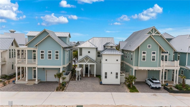 exterior space with a residential view, driveway, a garage, a standing seam roof, and metal roof