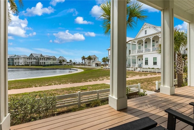 wooden deck with a water view, a residential view, fence, and a lawn