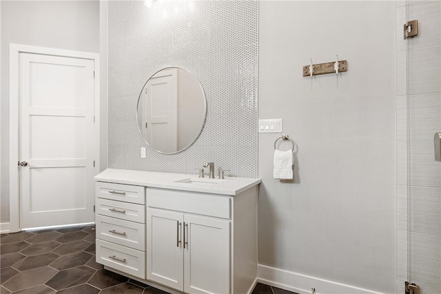 full bathroom with a shower with shower door, vanity, baseboards, and tile patterned flooring
