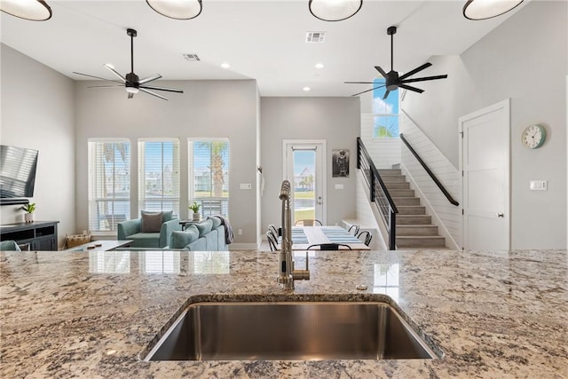 kitchen with a sink, visible vents, open floor plan, and a ceiling fan