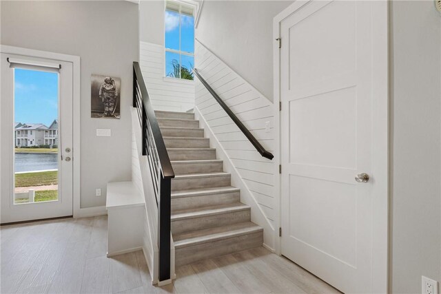 staircase featuring a water view, wood finished floors, and a healthy amount of sunlight
