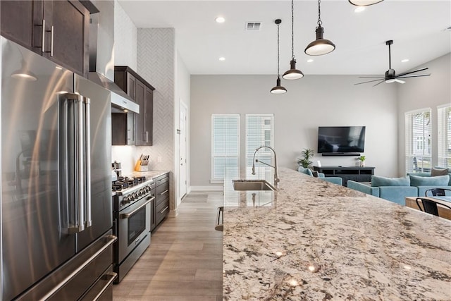 kitchen featuring visible vents, premium appliances, a sink, dark brown cabinetry, and light wood finished floors