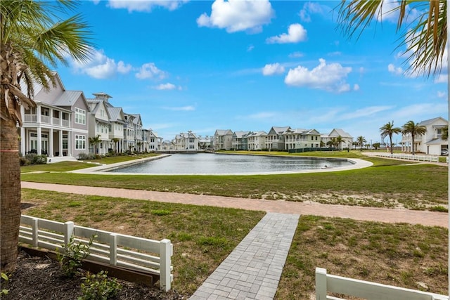 view of community featuring a yard, fence, a residential view, and a water view