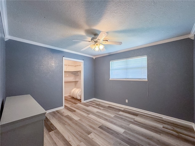 unfurnished room with ornamental molding, light wood-type flooring, a textured ceiling, and ceiling fan