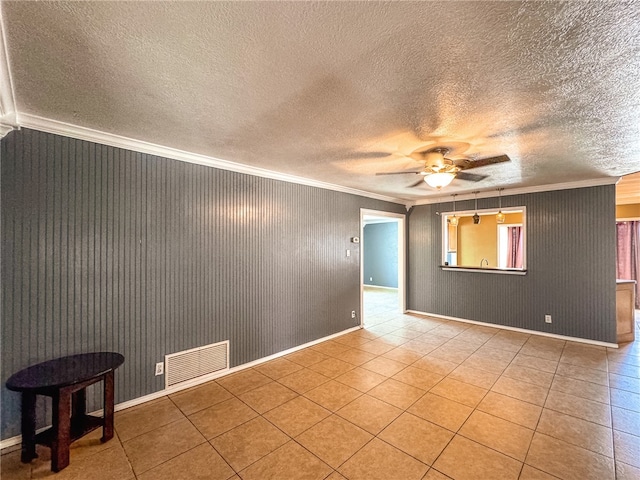 empty room with light tile patterned flooring, ceiling fan, a textured ceiling, and ornamental molding