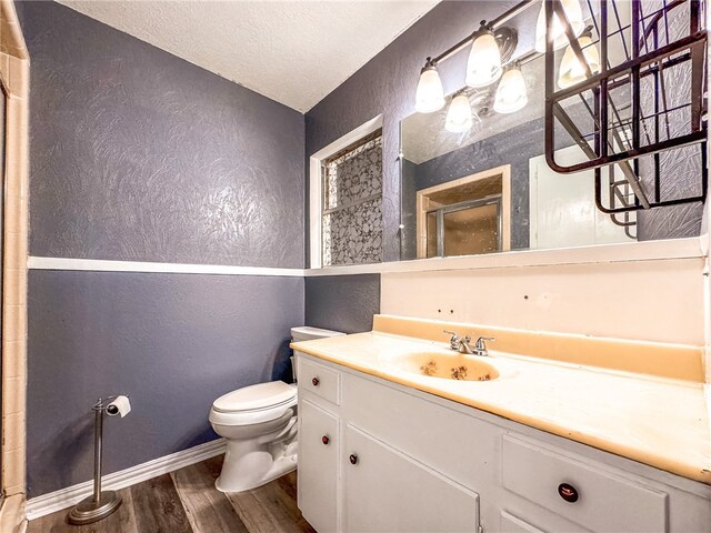 bathroom featuring a shower with door, a textured ceiling, hardwood / wood-style floors, vanity, and toilet