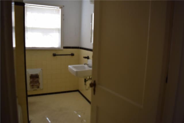 bathroom featuring tile walls, a wainscoted wall, and a sink