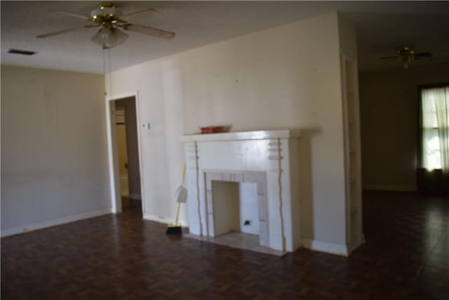 unfurnished living room with visible vents, baseboards, a fireplace, and a ceiling fan