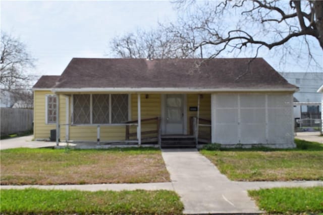 view of front of house featuring covered porch, a front lawn, and fence