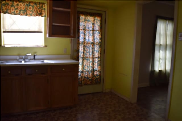 kitchen with a sink, baseboards, and light countertops