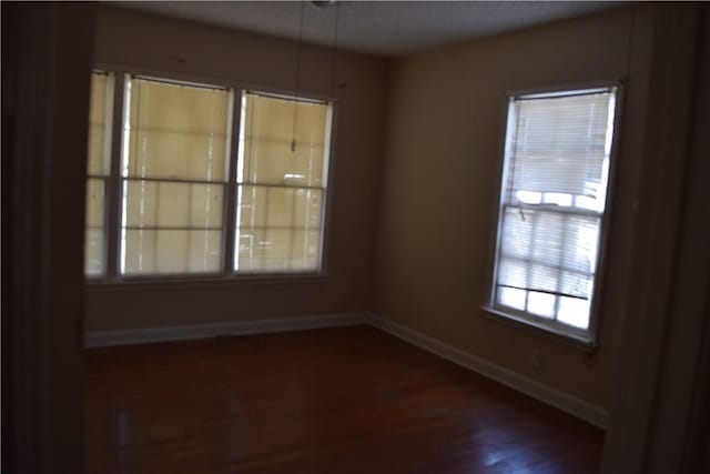 unfurnished room featuring dark wood-type flooring and baseboards