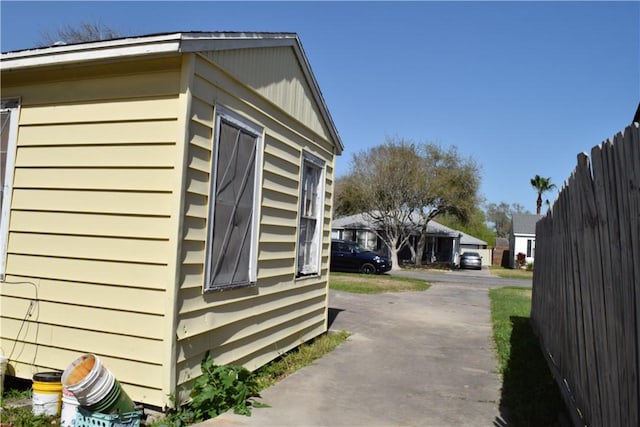 view of side of home featuring fence and driveway