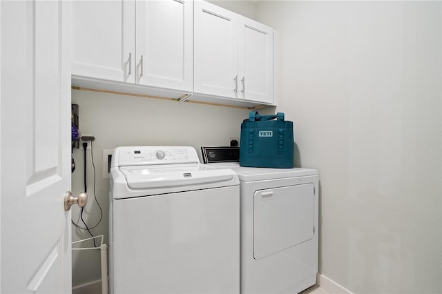 clothes washing area featuring cabinets and washing machine and clothes dryer