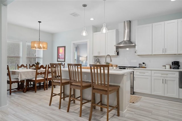 kitchen featuring range, white cabinetry, pendant lighting, and wall chimney range hood