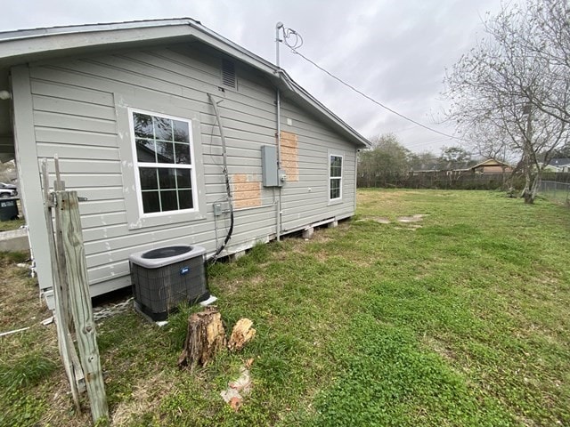 view of side of property with cooling unit and a lawn