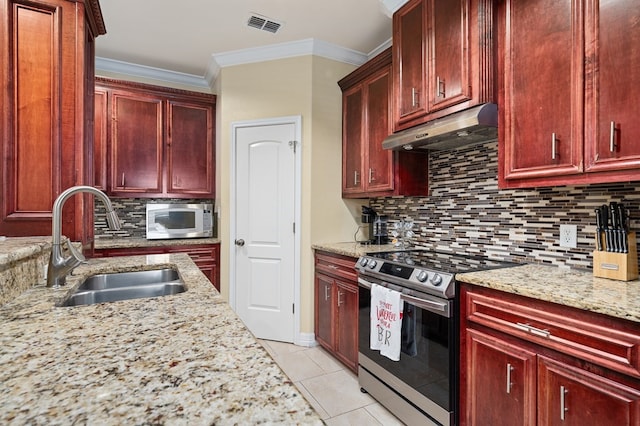 104 Sandollar Cir, Fulton, TX 78358 - kitchen with reddish brown cabinets, appliances with stainless steel finishes, under cabinet range hood, decorative backsplash, and light stone countertops