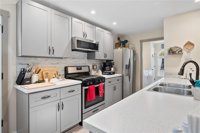 kitchen with decorative backsplash, light wood-type flooring, stainless steel appliances, and sink