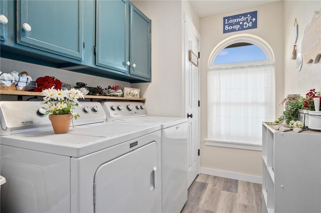 washroom with washer and clothes dryer, cabinets, and light hardwood / wood-style flooring