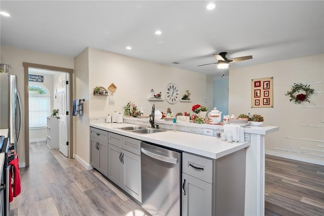 kitchen with gray cabinetry, ceiling fan, sink, appliances with stainless steel finishes, and light wood-type flooring