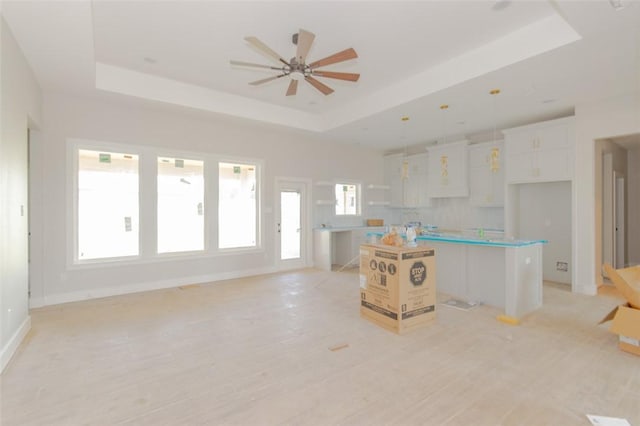 3005 Saint Eustatius Way, Corpus Christi, TX 78418 - kitchen featuring a raised ceiling, a kitchen island, white cabinets, decorative light fixtures, and light wood-style flooring