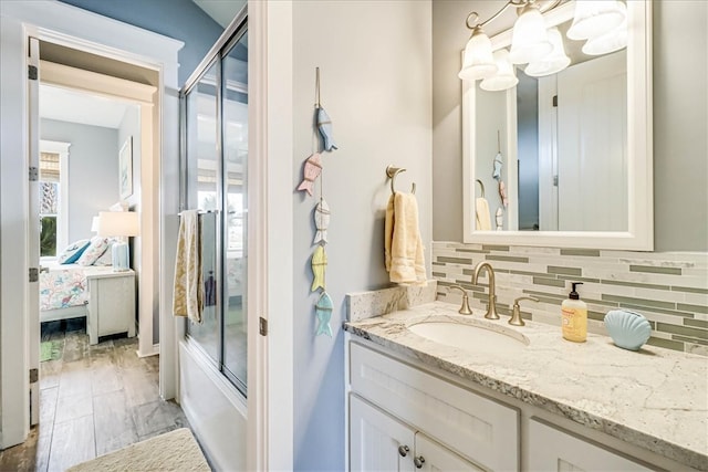 bathroom with backsplash, vanity, and enclosed tub / shower combo