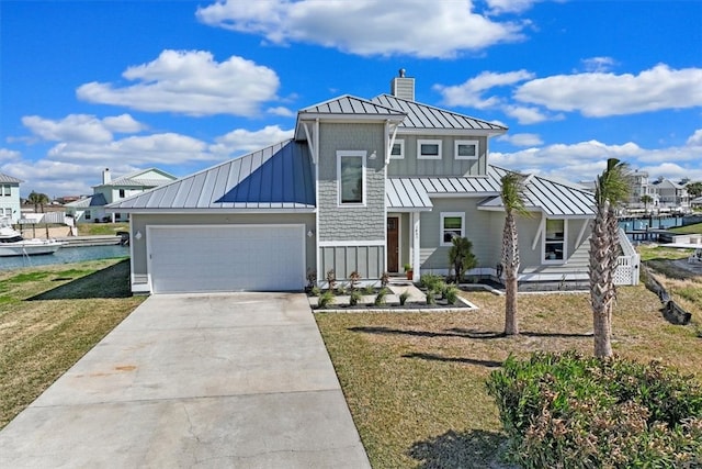 modern farmhouse featuring a front yard, a water view, and a garage