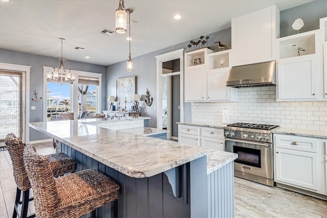 kitchen with a kitchen breakfast bar, wall chimney exhaust hood, stainless steel stove, and a kitchen island