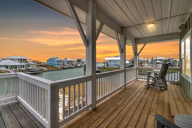 deck at dusk featuring a water view