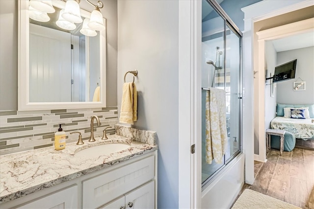 bathroom with vanity, tasteful backsplash, bath / shower combo with glass door, and hardwood / wood-style floors