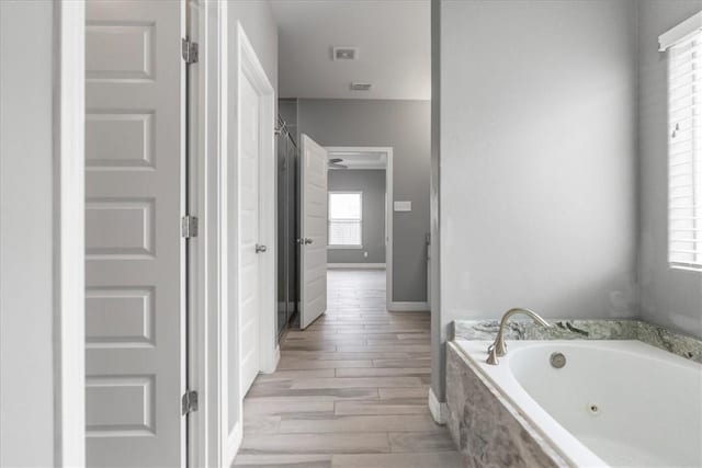bathroom with a whirlpool tub, wood finished floors, and baseboards