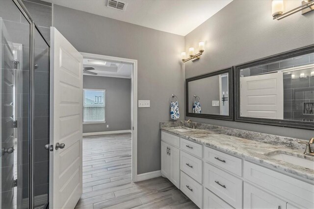 bathroom with a stall shower, double vanity, baseboards, and wood finished floors