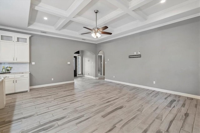 unfurnished living room with arched walkways, coffered ceiling, beamed ceiling, ceiling fan, and light wood-style floors