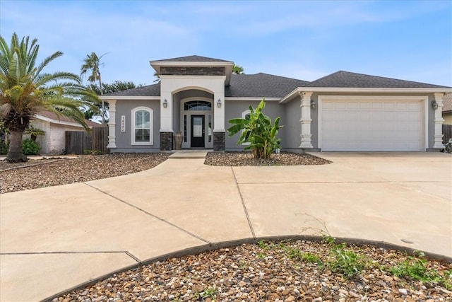 view of front of property with driveway, an attached garage, stucco siding, roof with shingles, and fence