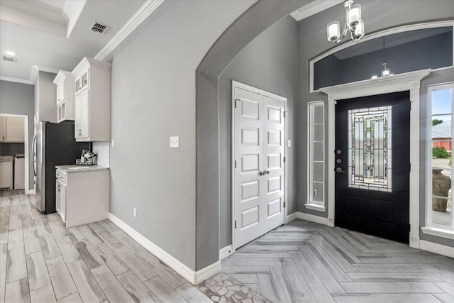 entrance foyer with arched walkways, a chandelier, baseboards, ornamental molding, and light wood-style floors