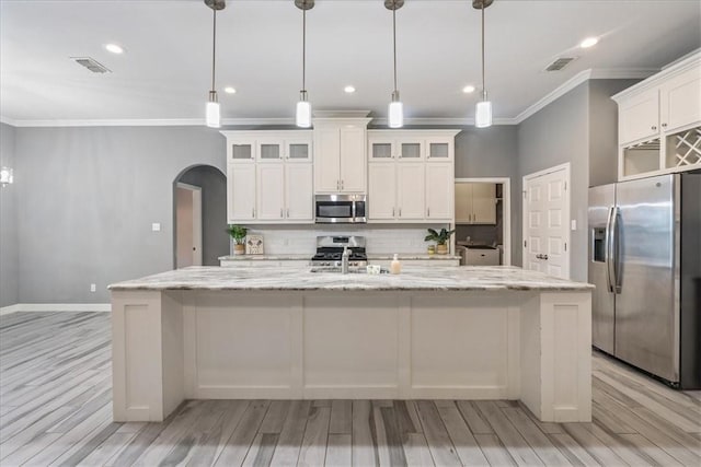 kitchen with appliances with stainless steel finishes, arched walkways, crown molding, decorative backsplash, and light wood-style flooring