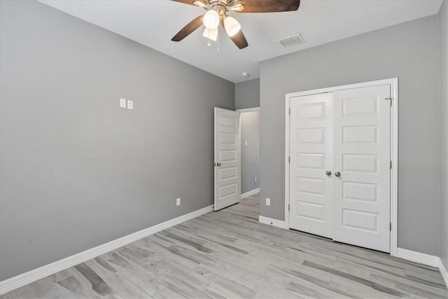 unfurnished bedroom featuring light wood finished floors, baseboards, a closet, and a ceiling fan